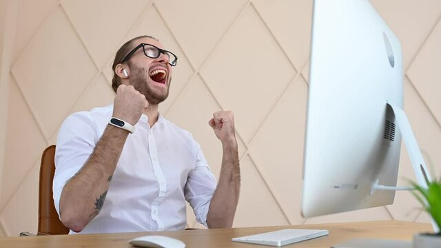 Ecstatic male office employee celebrating work achievement professional win, overjoyed guy screams yes with triumph looking the laptop screen