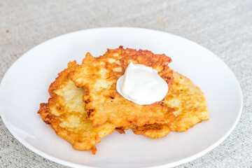 Potato pancakes, raggmunk, draniki, deruny, latkes or boxties on white plate. Polish placki ziemniaczane with sour cream.