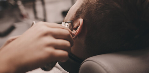 oung man getting beard haircut by hairdresser