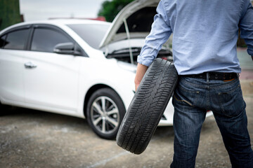 A man holding a spare tire preparing to repair Or change by yourself, the idea of ​​changing tires when entering the rainy season and winter