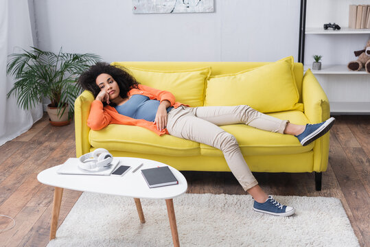 bored african american woman chilling on yellow couch