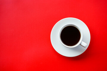 Flat lay view of dark hot coffee cup on red background with copy space 