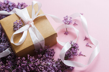 Obraz premium Lilac flowers and gift box on pink paper. Happy mothers day and womens day