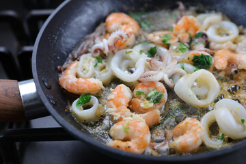 frying seafood and herbs on pan