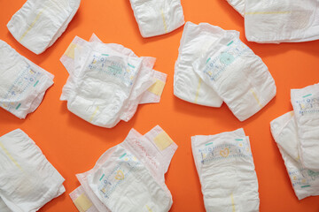 Baby diapers collection on orange color background. - obrazy, fototapety, plakaty