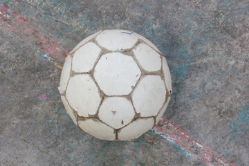 Old used football or soccer ball on cracked asphalt