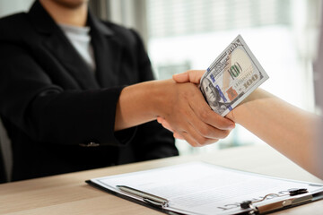 Business woman or accounting officer Shaking hands to gladly offer and accept a bribe offer. Cash from Partners in Collective Finance Agreement, Concept of Bribery Dirty Money in Workplace