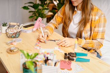 Fototapeta premium Cropped shot of women making homemade scrapbooking album from paper. DIY, hobby concept, gift idea, decor with handcraft attributes, home production, the process of creation, creativity.