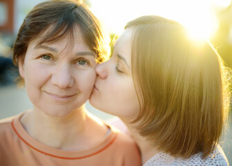 Loving adult daughter hugs and kisses her mature mom. A tender relationship between an grown up child and a parent