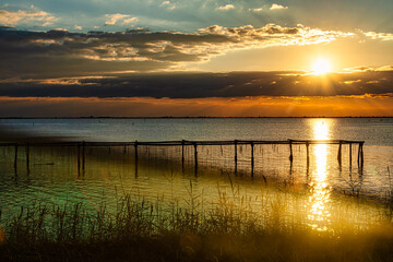 Fototapeta na wymiar Breathtaking sunset in Po Delta with Stilts for Shell fishing, Italy