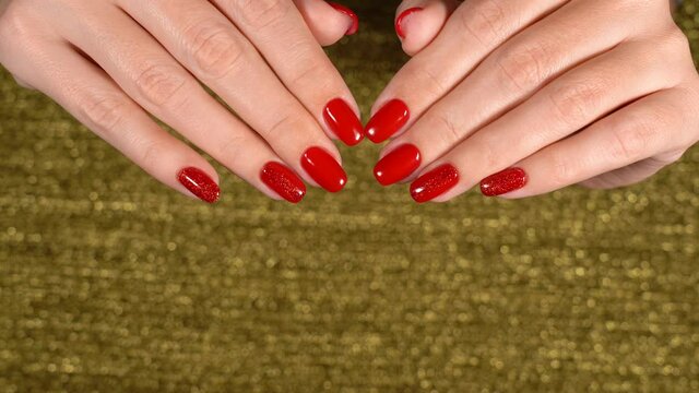 Woman looks at her fresh glossy professional manicure. Close up view 4k video of hands and fingers with beautiful red polish on short elegant natural nails. Point of view footage