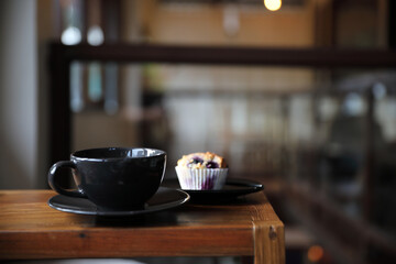 Coffee cup with muffin on wood table in local coffee shop