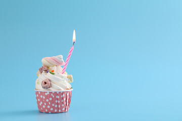 Colorful cupcake with candle isolated in blue background