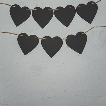 Black paper hearts on grey background. Valentine's day loft concept.