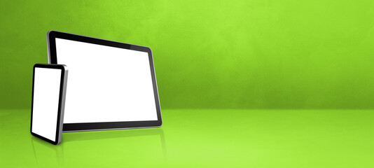 Mobile phone and digital tablet pc on green office desk. Background banner