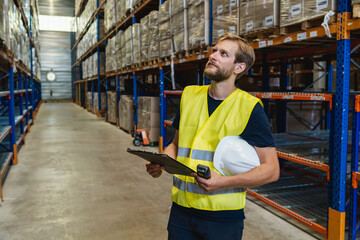 young warehouse manager checking goods using a clipboard in a warehouse