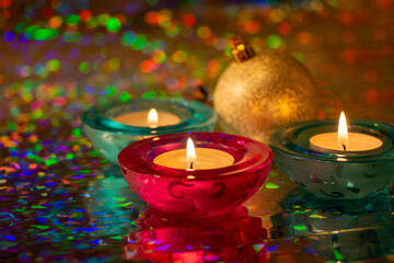Decorative candles and christmas ball on colored blurred background