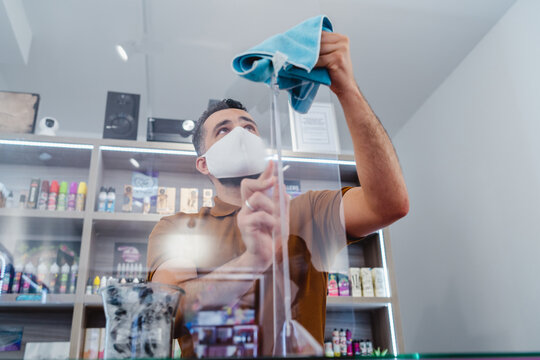 Retail Store Manager Cleaning Protective Glass During Virus Pandemic