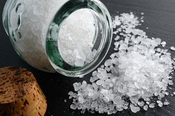 Sea salt in small glass jar on black background