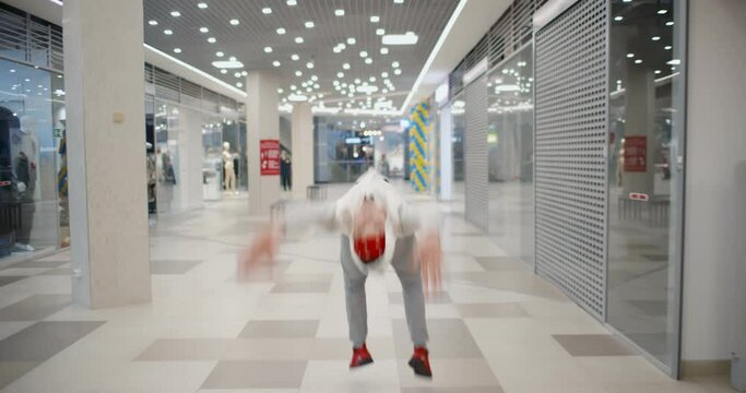 Breakdancer doing back flips in hallway of modern shopping mall