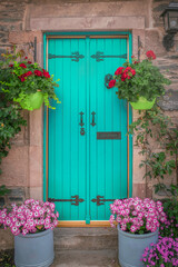 Fototapeta na wymiar Vibrant Blue Cottage Door With Colourful Flower Baskets