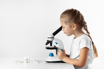 Child looking through microscope on white background. Kid scientist learning biology.