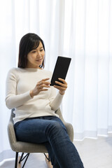 Woman sitting in a chair and holding a tablet