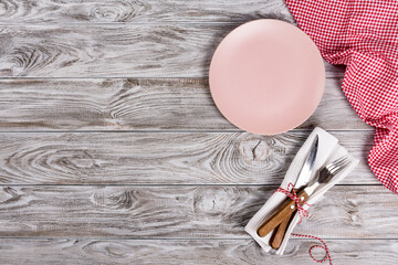 Pink empty plate and fork and knife on wooden texture background. Romantic dinner concept.