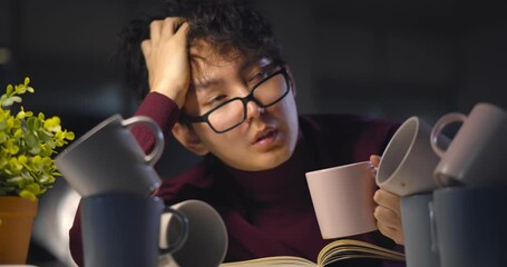 Tired student doing homework indoors late at night with many empty coffee cups on table