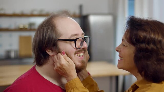 Senior pleasant woman touching her son cheek while showing her affection