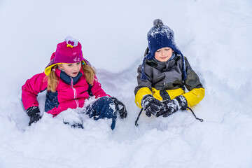 Children Enjoying Snowfall and Playing in the Snow. Winter holiday. Outdoor games. Warm clothes cozy hat in cold weather.