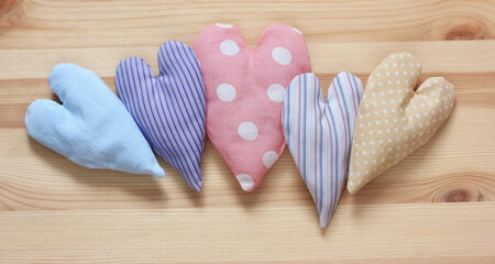 five rag hearts on a wooden table, top view.