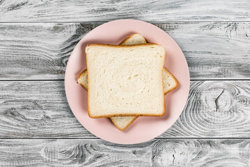 White bread toast on pink plate on wooden background
