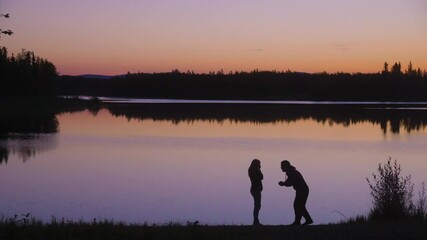 Man proposing to woman by lake at dawn