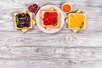 Delicious toasts with various sweet jams on grey background. Copyspace for your text, banner.