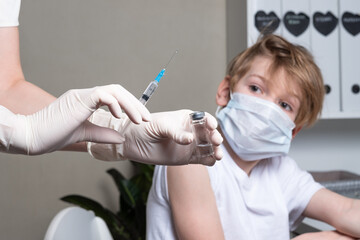 Doctor's Hand in white gloves hold the vial with vaccine or drug and syringe on blue background. The concept of protection against coronavirus infection, COVID-19. Banner
