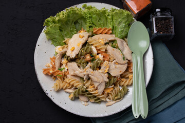 Macaroni stir fried with chicken in ceramic plate on black background