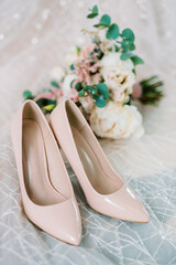composition - wedding pink pumps shoes on the background of fabric and a wedding bouquet.