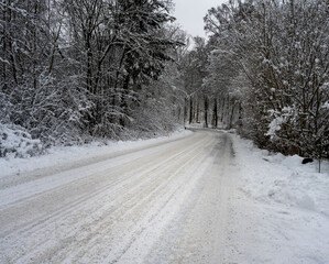 Obraz premium An icy and snowy winter road going through a forest. Picture from Scania, southern Sweden