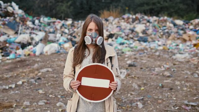 Portrait of Sad Young Woman in Gas Mask Holding Stop Sign While Standing in Toxic Smoke. Activists Worry About Environmentalism. Saving the Planet.