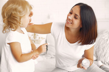 Beautiful woman with child. Woman in a white t-shirt. Mother with doughter using a cosmetics.