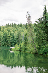 A picturesque place - a wooden pier on a forest lake among the trees. Summer season and outdoor recreation.