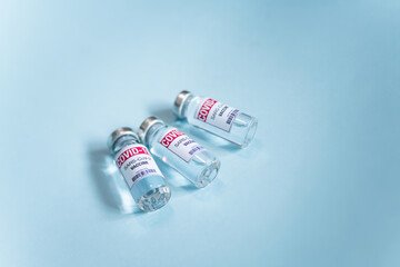 Covid-19 vaccine. Ampoules with coronavirus Sars-Cov-2 jab Injections. Vaccine shortages setback for Its immunization race. Close up vial dose on blue background and place for text. 
