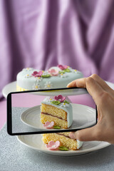 Woman making photo of fondant decorated celebration cake with her phone on purple