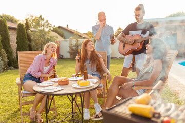 Friends singing and playing the guitar at backyard barbecue party