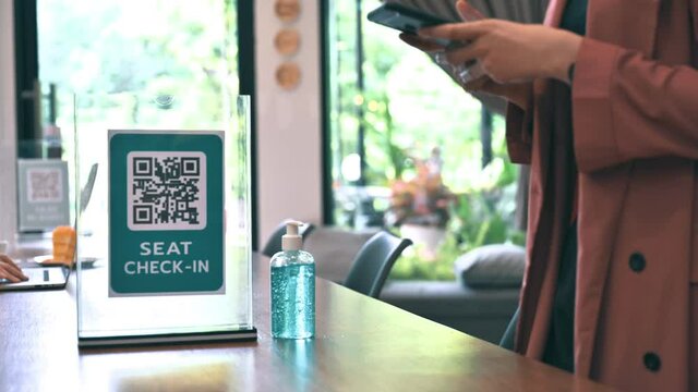 female scan check-in QR code by smartphone app and cleansing hand by alcohol gel before entering coffee shop. concept of new normal coronavirus prevention