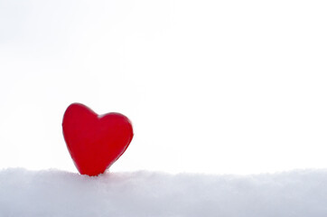 Fototapeta na wymiar Beautiful red heart in the snow on a light background. Valentines day concept