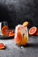 orange juice with ice and thyme on black background