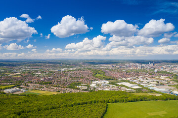 Fototapeta premium Aerial photo of the city of Leeds viewed from the village of Middleton and Middleton Park on a sunny day with white clouds in the sky and a lot of green trees in the summer time
