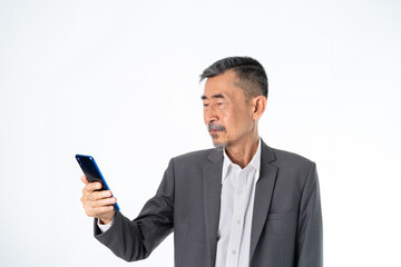 Happy Senior old Asian businessman in grey suit texting and uses the social network on a cell phone. And online Shopping, online technology for the active elder concept. Over white background